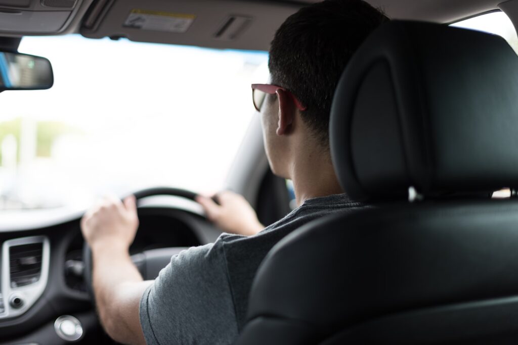 Blick von der Rückbank auf den Fahrer am Lenkrad (KI-generiertes Symbolbild)