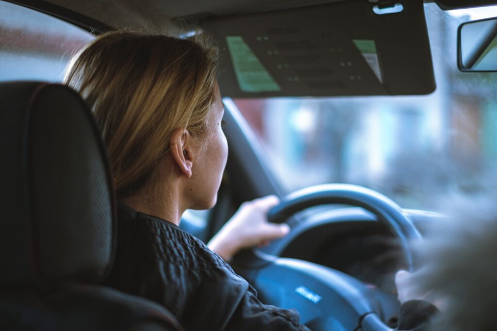 Junge Frau am Steuer eines Autos während einer Fahrstunde (KI-generiertes Symbolbild)